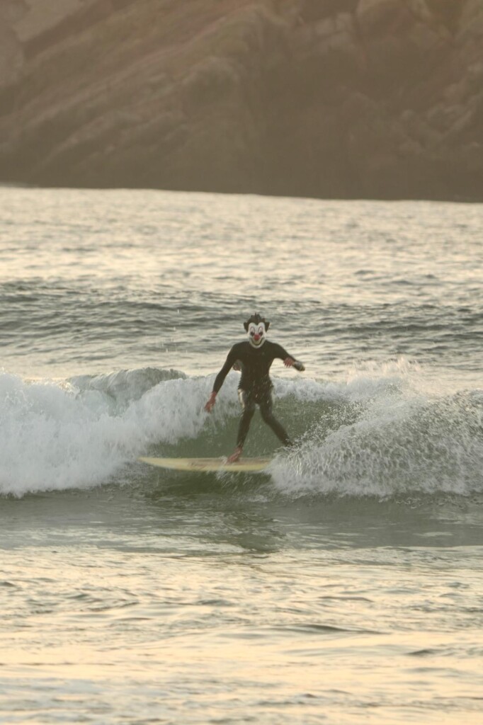 2 Surfista con máscara de payaso cogiendo una ola en Halloween